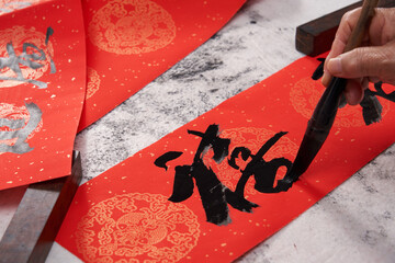 An old calligrapher writes couplets during the Chinese Year of the Dragon.
Translation: joy.
