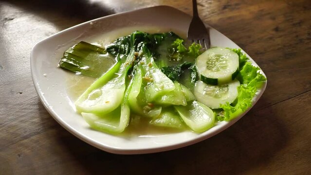 Green mustard served with cucumber slice on plate. Stir fry Chinese cabbage. Smoky fresh vegetable served on plate