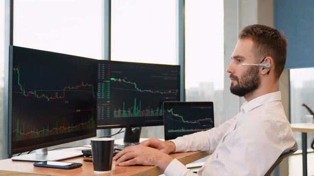 Trader or broker in formal wear working with charts and market reports on computer screens in his modern office