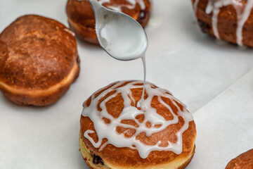 Zbliżenie na pączki podczas polewania białym lukrem z cukru pudru i cytryny