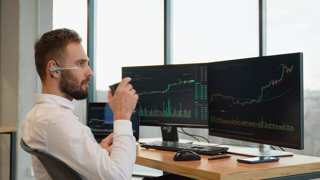 Concentrated trader sitting in front of computers, making professional analysis of candlestick chart, creating strategy