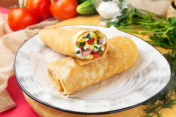 Pancake stuffed with ham, tomato, cheese on a plate. Fast food