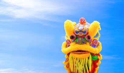 Colorful yellow Chinese lion dance against blue sky background while showing performance on street in Chinese New Year festival