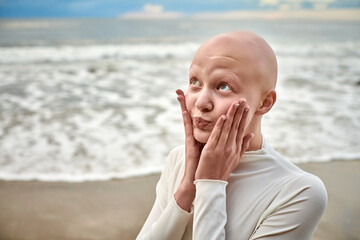 Hairless girl with alopecia make faces in white futuristic costume on sea background