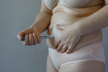 Woman making Semaglutide Injection closeup. Semaglutide or insulin Injection pen in female belly. Semaglutide Diabetes Drug Being Used For Weight Loss. - obrazy, fototapety, plakaty