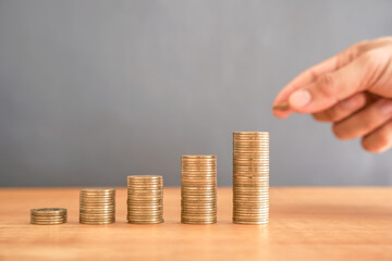 Golden money coin stack and hand holding coin to stack. Saving money and financial concept. 