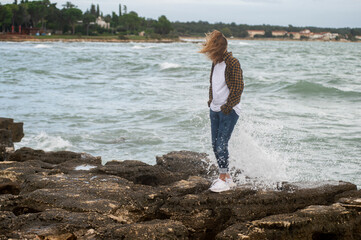A woman stands on the coast of the Adriatic Sea in cold and windy weather