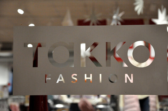 Takko Fashion: Etikett mit Aufschrift f&uuml;r die Modefiliale am Schaufenster.