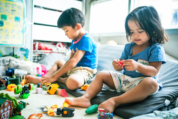 Toddler girl play car toy with boy in cozy room