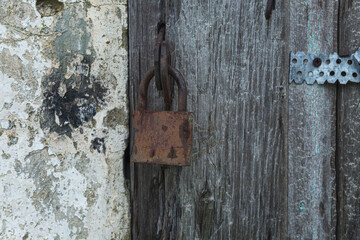 An old padlock on a gray stripped wooden gate. Protect property and privacy. Close-up.
