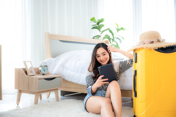 Obraz premium Close up of Attractive cute woman is planning and arranging for her vacation holiday trip by tablet in her apartment or condo, enjoyment and happiness lifestyle, wellbeing relaxation weekend journey.