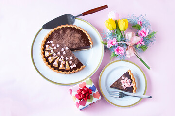 バレンタインのお菓子　手作りチョコレート・タルトと贈り物とチューリップと桃のリース（ペールピンクの背景）