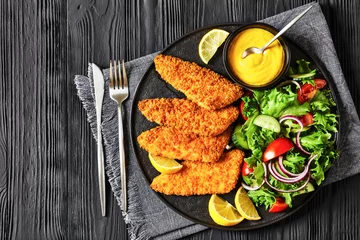 Gordijnen breaded fish fillet with salad on black plate © myviewpoint