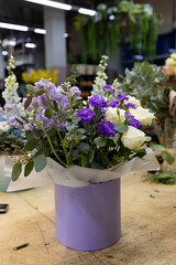 The composition of a bouquet of cream and purple roses and greenery