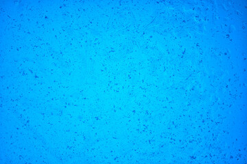The surface texture of thin ice illuminated from within by blue light. There are some bubbles and scratches. Background.