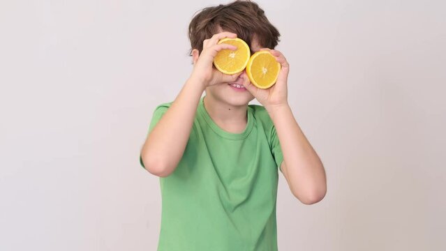 A young boy holds orange slices to his eyes, highlighting the importance of vitamins for health. Imagining oranges as eyes, the photo speaks to the clarity vitamins bring to health.
