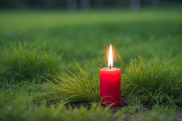 Red candle on green grass, blurred grass background - Powered by Adobe