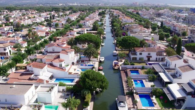 Drone shot of canals of Empuriabrava. Vacation haven with prime real estate for sale. Waterways with private boats next to luxurious summer houses. 