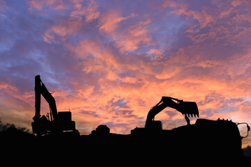 Crawler excavators silhouette are digging the soil in the construction site. on  sky cloud...
