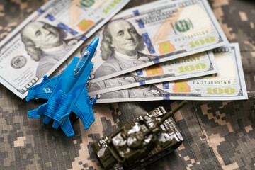 Toy tank on US hundred dollar bills banknotes close up. The concept of war costs, military spending and economic crisis