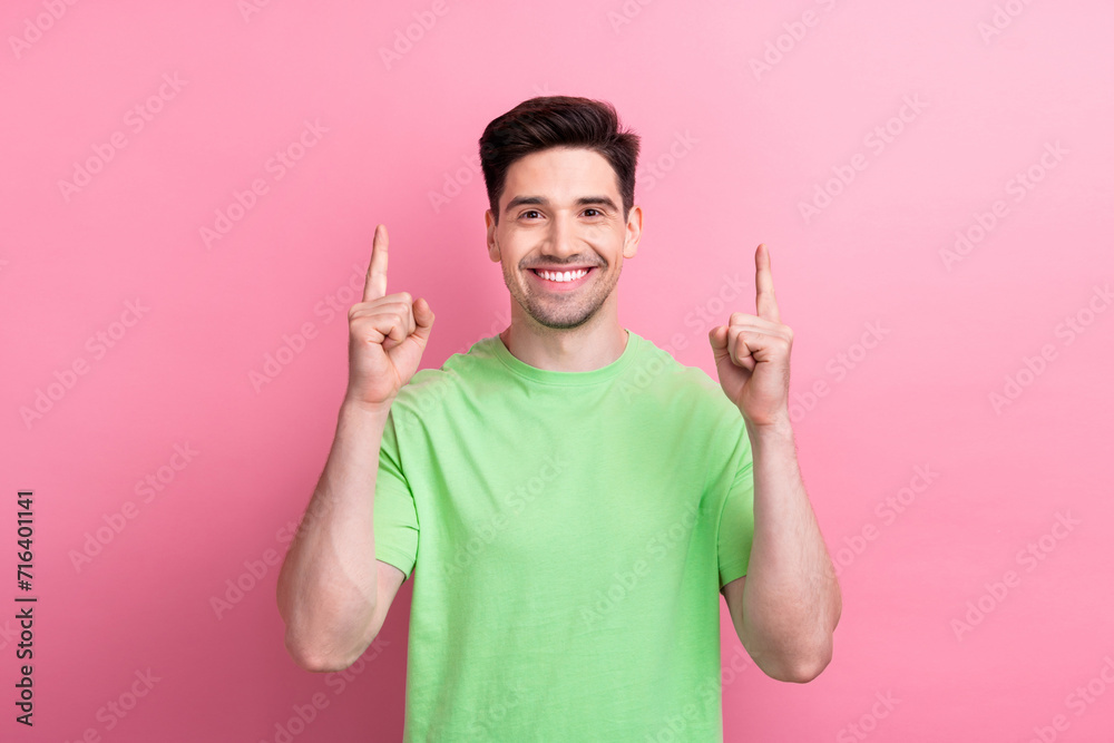 Wall mural photo of cheerful nice man wear green clothes presenting empty space banner novelty isolated on pink