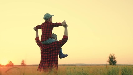 Child, boy, is sitting on farmers dads shoulders play dream of fly. Happy family father, son play...