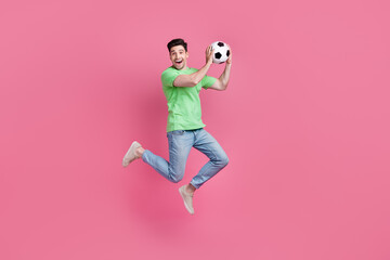 Fototapeta na wymiar Full body photo of funny young man jumping trampoline hold football ball remember his goalkeeper skills isolated on pink color background