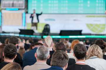 Blurred view of attentive audience listening to speaker at a business seminar in a modern conference hall.