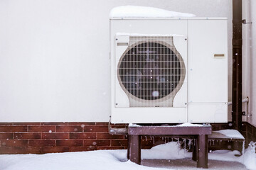 Heat Pump Snow Covered by External Wall of Residential Building in Winter. Modern Cost Effective...