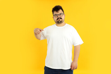 A man with a blank white t-shirt, on a yellow background.