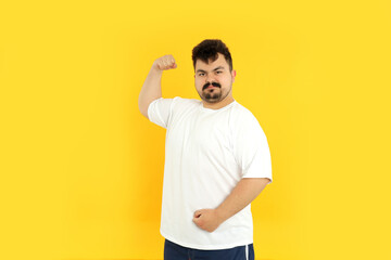 A fat man shows his muscles, on a yellow background.