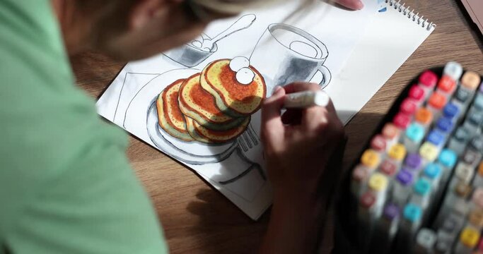 Person draws picture with eating pancakes and cup at home. Home hobbies entertainment and drawing