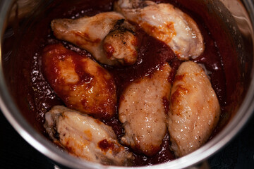 Baked chicken wings covered in barbecue sauce. Glaze application stage