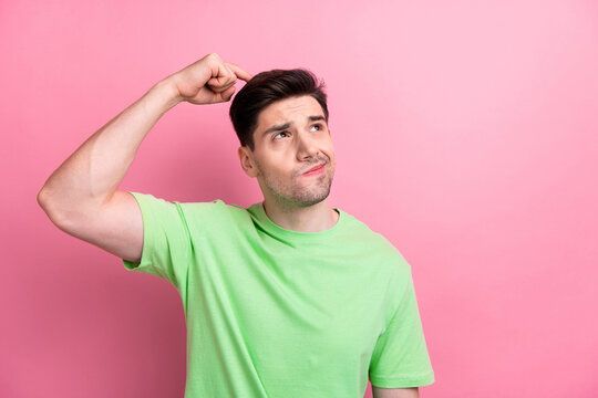 Photo of young funny man failed thinking and scratching head confused looks empty space solving problem isolated on pink color background