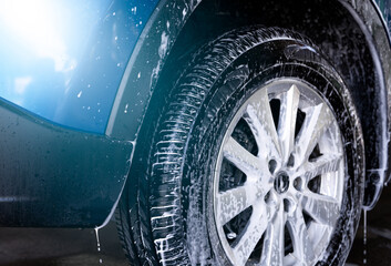 Blue car wash with white soap foam and professional auto care service. Car cleaning service...