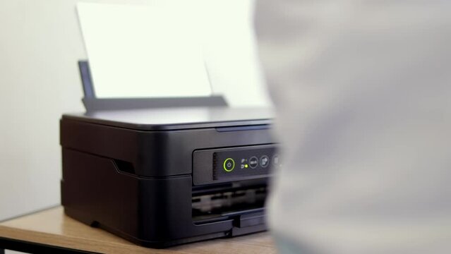 a man puts white paper into the printer, Laser printer in operation. Close-up of printing on paper. High quality 4k footage