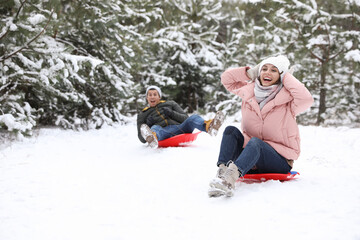 Fototapeta na wymiar Happy couple sledding outdoors on winter day. Christmas vacation