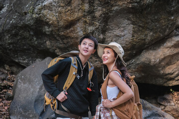 An Asian couple spent their vacation hiking along nature trail, visiting waterfall and enjoying forest views together.