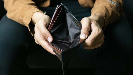 Poor man bankrupt with no credit in debt hand hold empty black leather wallet because economy down...