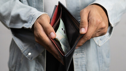 Poor man bankrupt with no credit in debt hand hold empty black leather wallet because economy down...