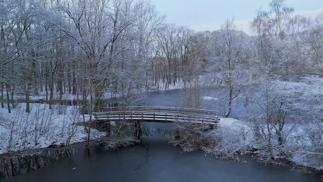 Flying through trees in winter snow landscape towards over frozen river