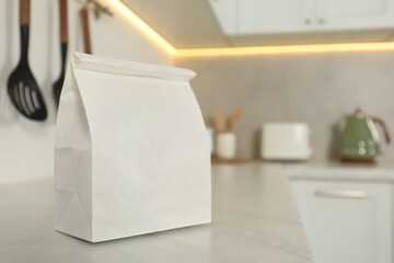 Paper bag on white countertop in kitchen, space for text