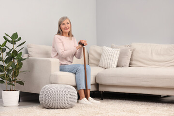 Obraz premium Mature woman with walking cane on sofa at home
