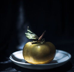 tendu is a seasonal fruit available mainly in summer,Luuk-jan fruit (Diospyros decandra) also known as Gold Apple, top view and isolated on dark background.Upward view, bunches of green raw Persimmon 