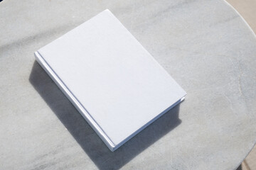 blank book for mockup design on marble table by the swimming pool - obrazy, fototapety, plakaty