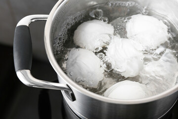 Fototapeta na wymiar Chicken eggs boiling in pot on electric stove, closeup