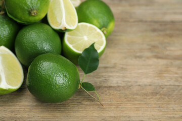 Pile of fresh limes on wooden table, closeup. Space for text