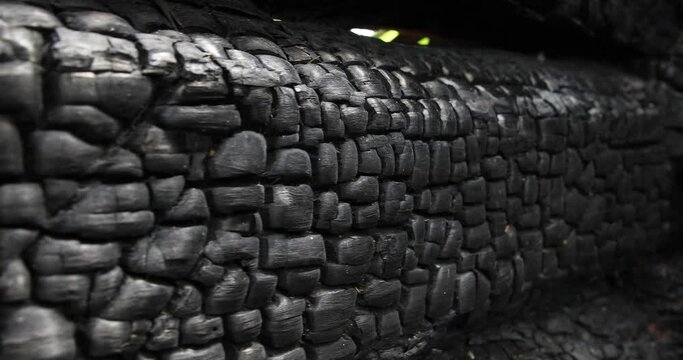 A wooden wall made of burnt logs after a fire.
