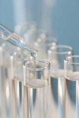 Laboratory analysis. Dripping liquid from pipette into glass test tube on blurred background, closeup