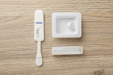 Disposable express test kit on wooden table, flat lay